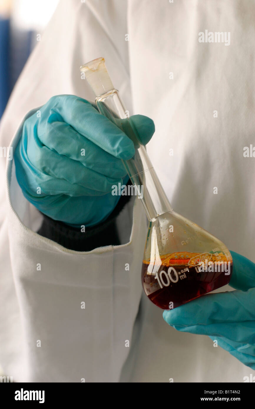 Gants en nitrile résistant aux produits chimiques utilisés pour traiter une fiole jaugée. Banque D'Images
