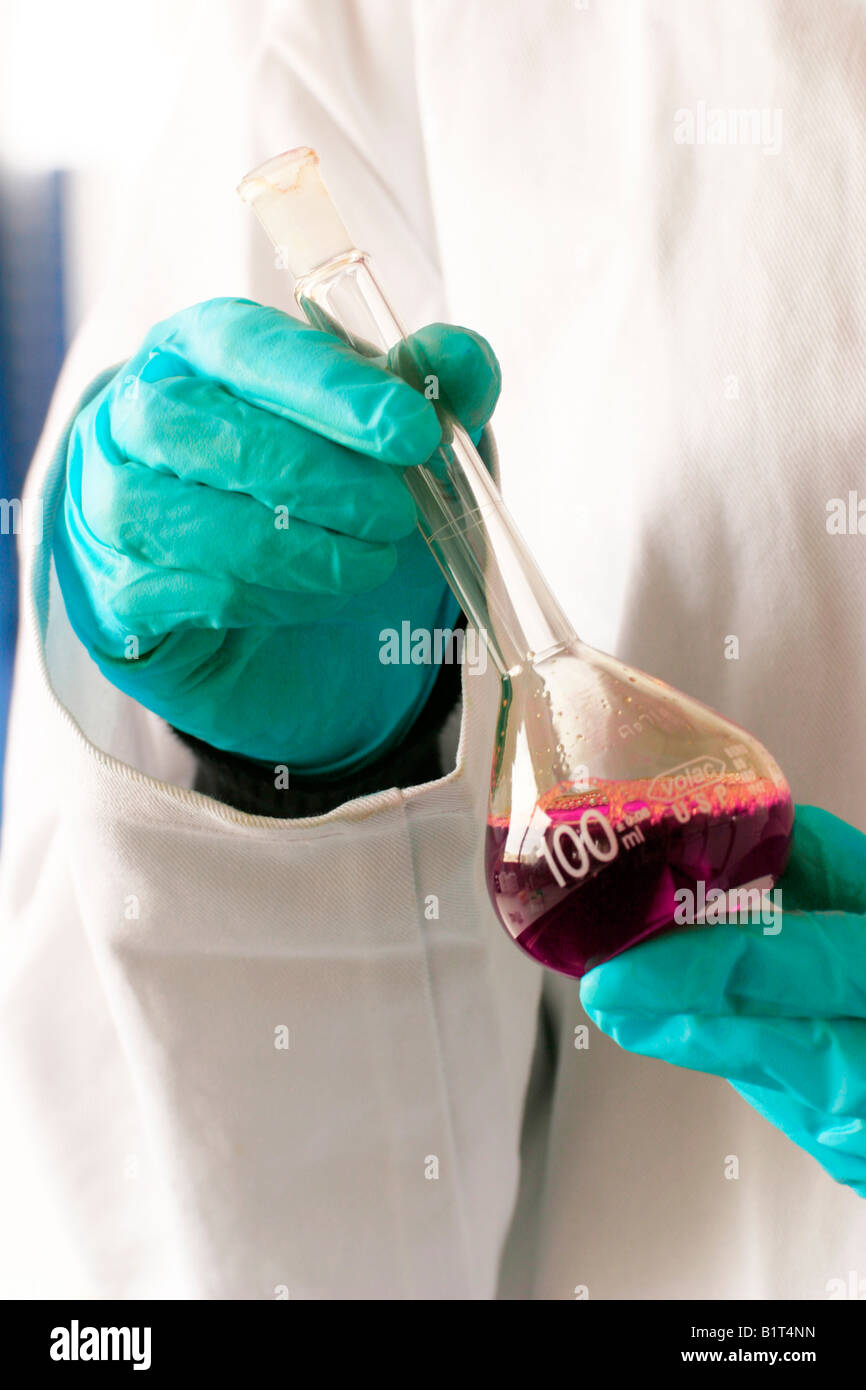 Gants en nitrile résistant aux produits chimiques utilisés pour traiter une fiole jaugée. Banque D'Images