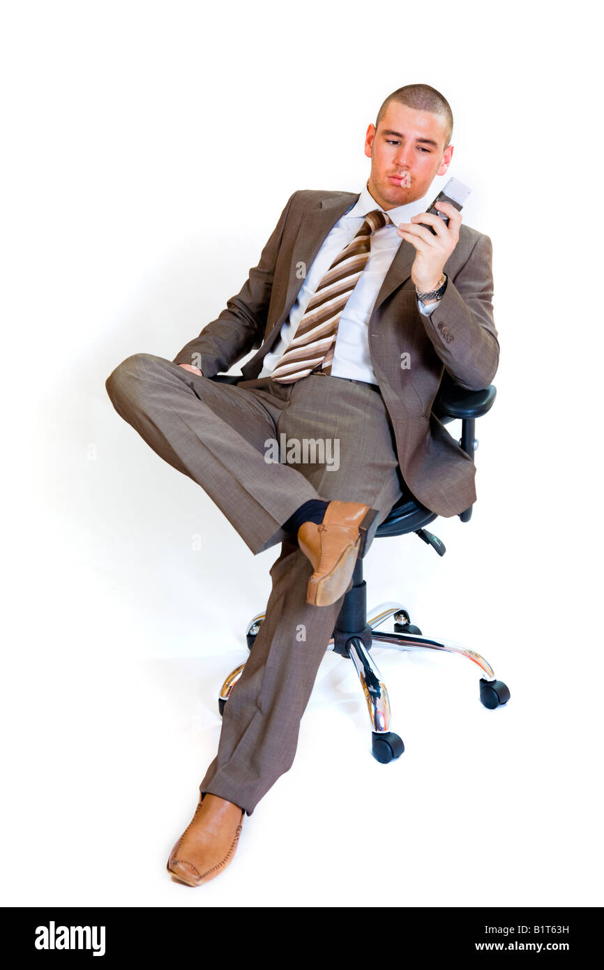 Jeune homme assis sur une chaise de bureau à l'aide d'un téléphone mobile. Banque D'Images