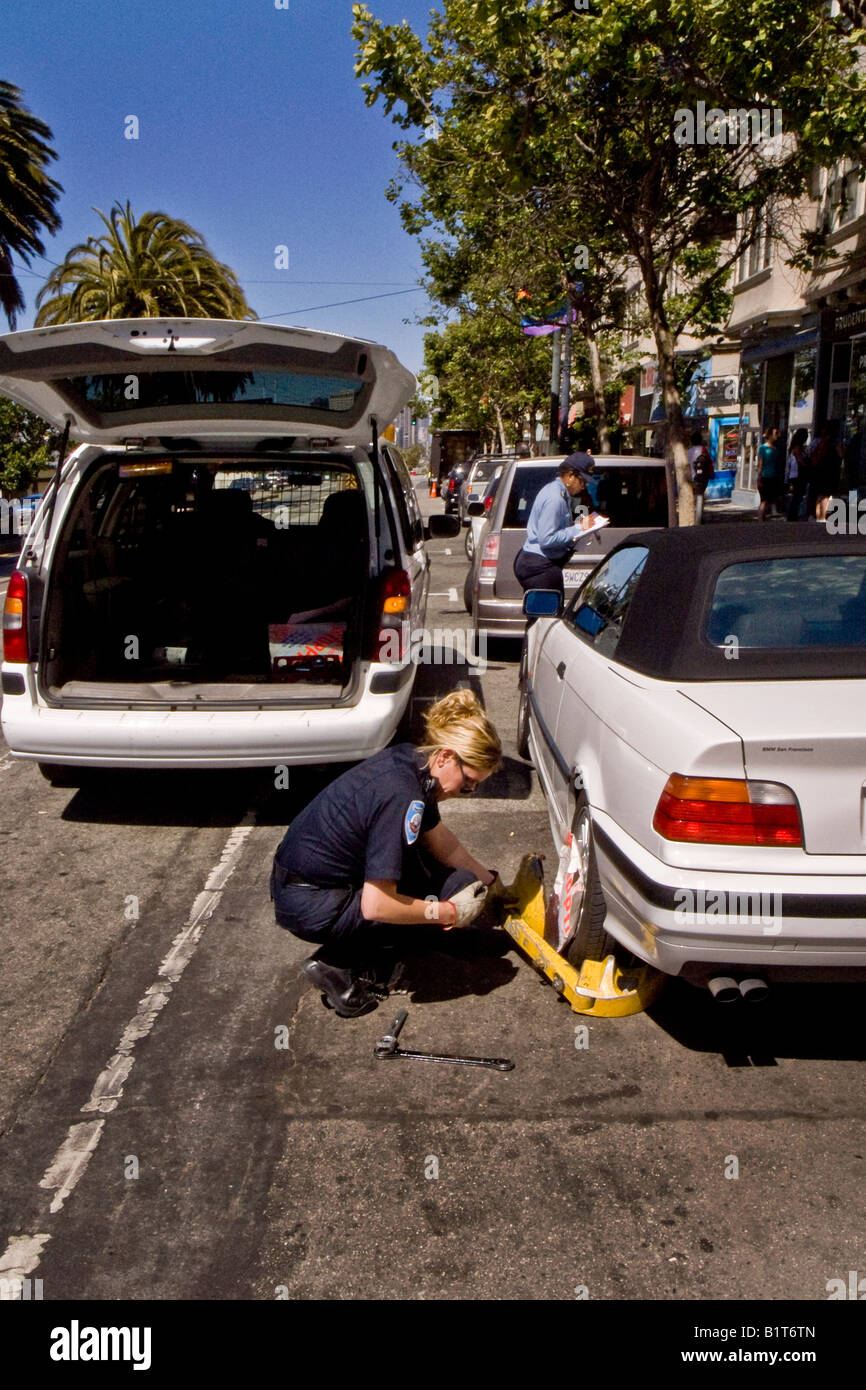 Parking Un agent de l'installe une roue antidémarrage ou boot sur une voiture avec des infractions de stationnement à San Francisco Banque D'Images