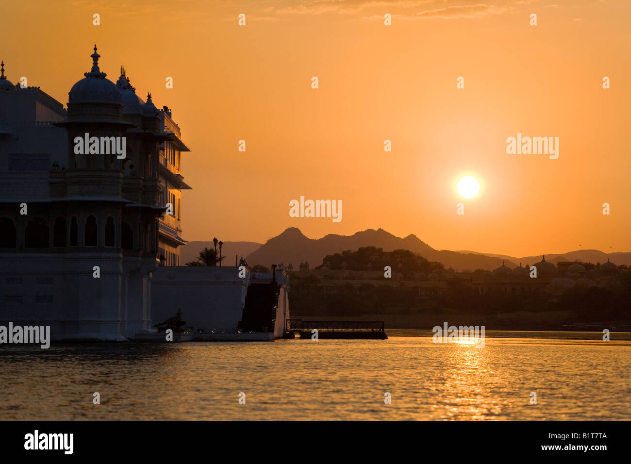 Coucher de soleil derrière le LAKE PALACE HOTEL sur JAGNIWAS ISLAND dans le lac Pichola construit par le Maharaja Jagat Singh ll UDAIPUR RAJASTHAN INDE Banque D'Images