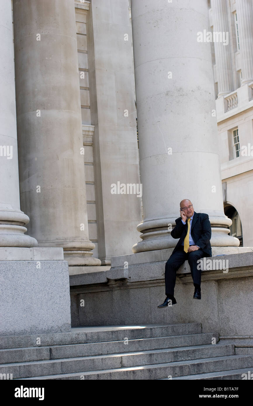Homme d'affaires faisant appel sur le téléphone mobile sur les marches de Royal Exchange City de Londres Royaume-Uni Banque D'Images