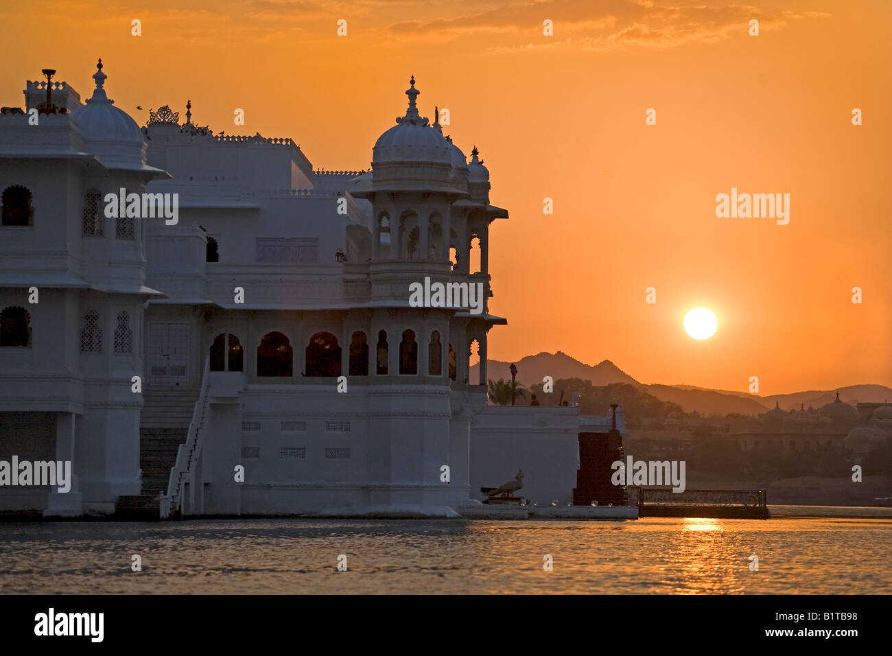 Coucher de soleil derrière le LAKE PALACE HOTEL sur JAGNIWAS ISLAND dans le lac Pichola construit par le Maharaja Jagat Singh ll UDAIPUR RAJASTHAN INDE Banque D'Images