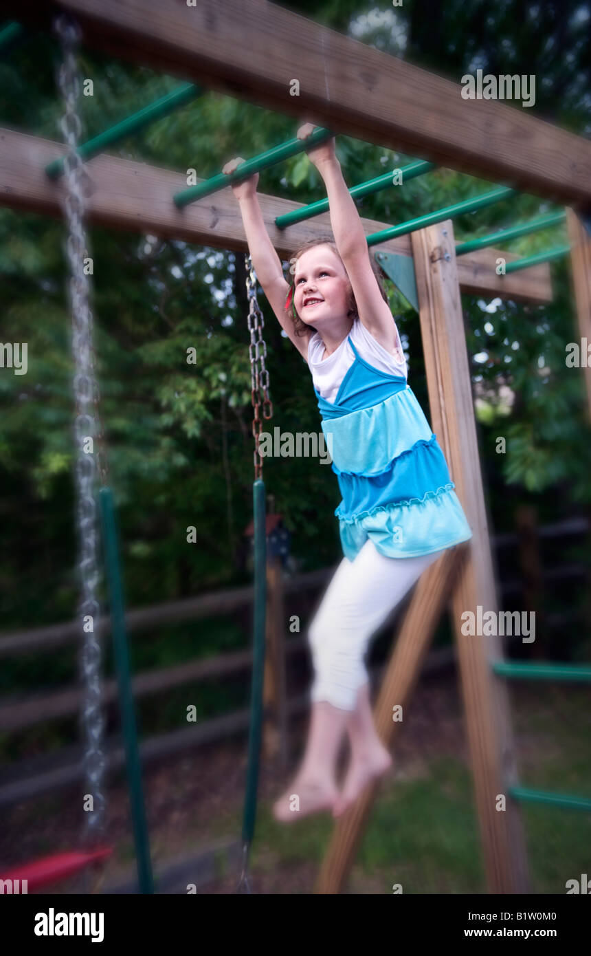 Girl climbing sur aire de jeu extérieur Banque D'Images