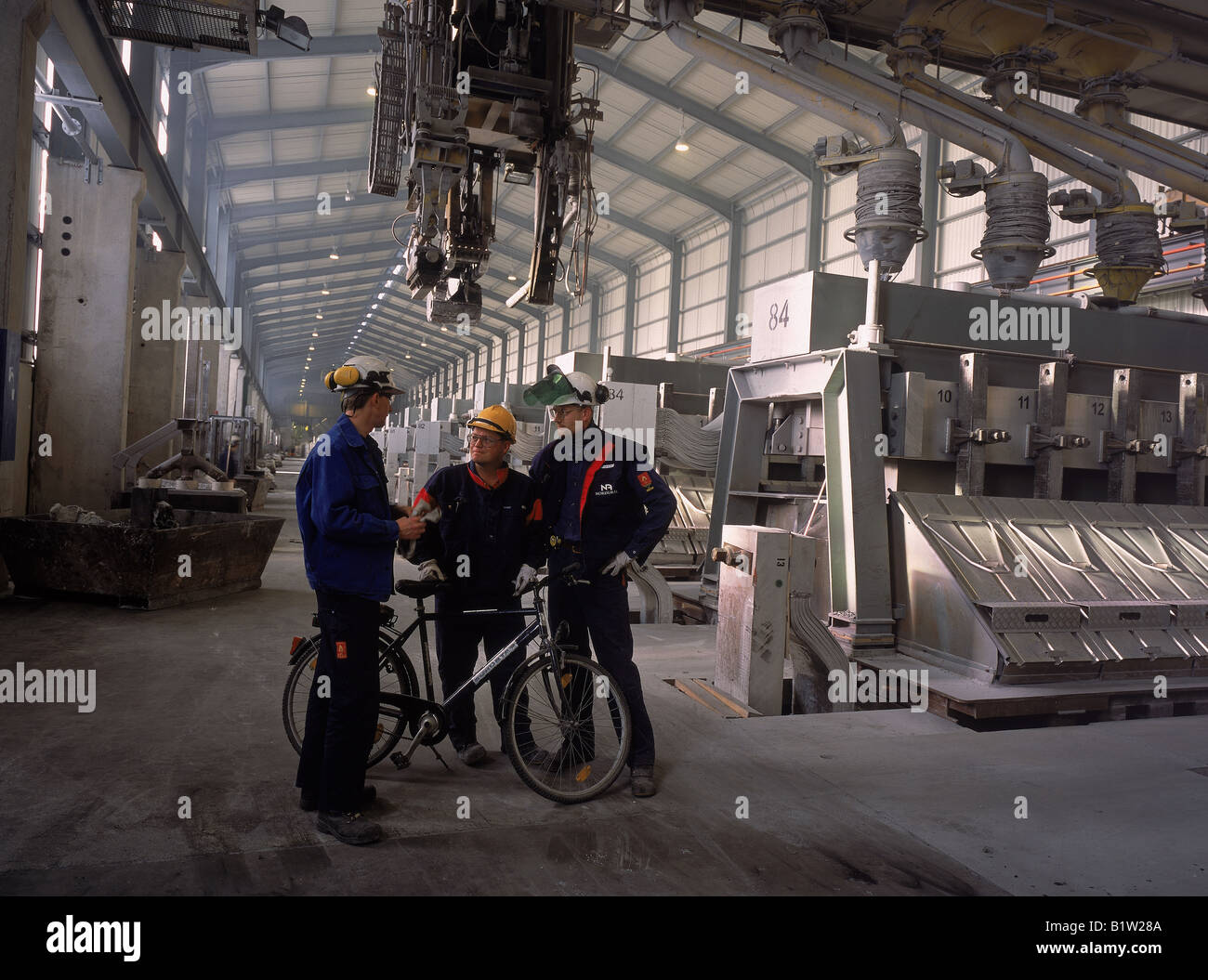 Travailleurs avec vélo dans l'usine d'aluminium Nordural, Islande Banque D'Images