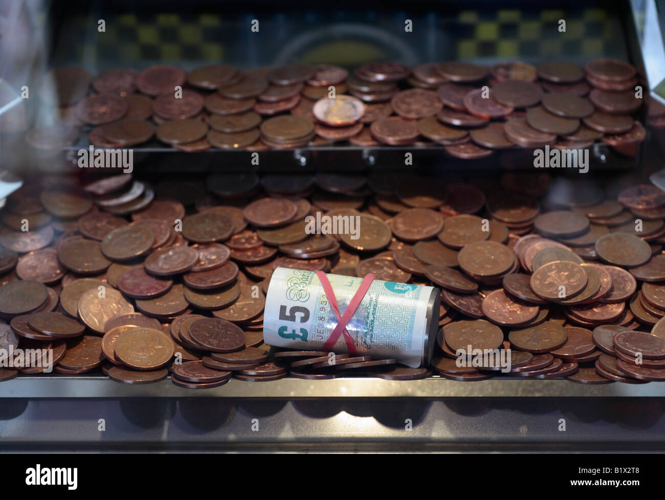 Une note de cinq livres (prix d'un penny tombe à une salle de jeux électroniques. Banque D'Images
