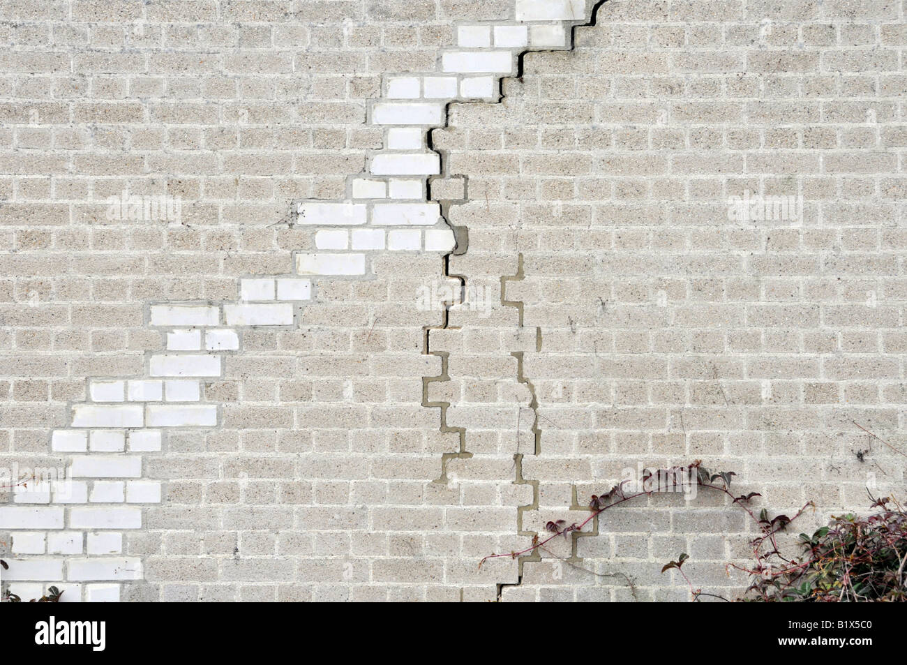 Mur de briques de la lumière de l'unité industrielle présente des signes de nouvelles fissures ainsi que des réparations antérieures Banque D'Images