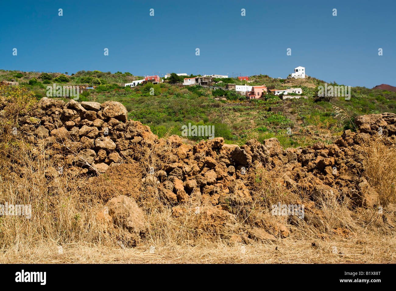 Paysage avec village sur une colline à El Hierro, l'effritement du mur de lave en premier plan Banque D'Images