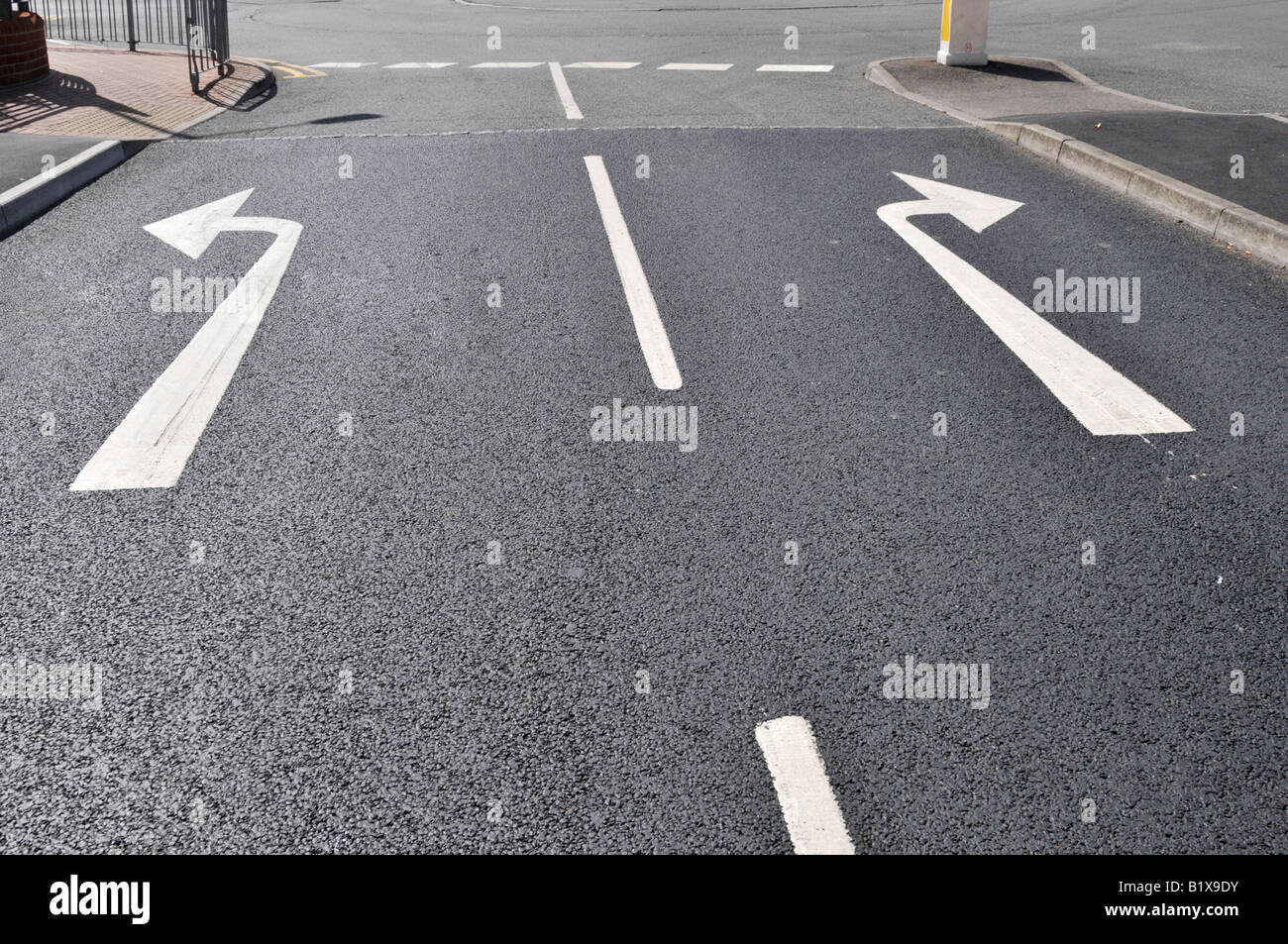 Décision choix Concept changement de sens de milieu de la route d'asphalte choix des flèches gauche et droite tournez à droite sur noir tarmac England UK Banque D'Images