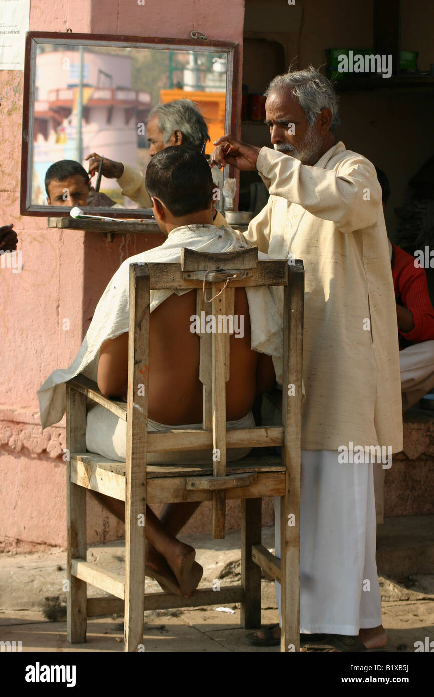 Salon de coiffure en donnant une coupe de cheveux sur un Ghat, Varanasi Banque D'Images