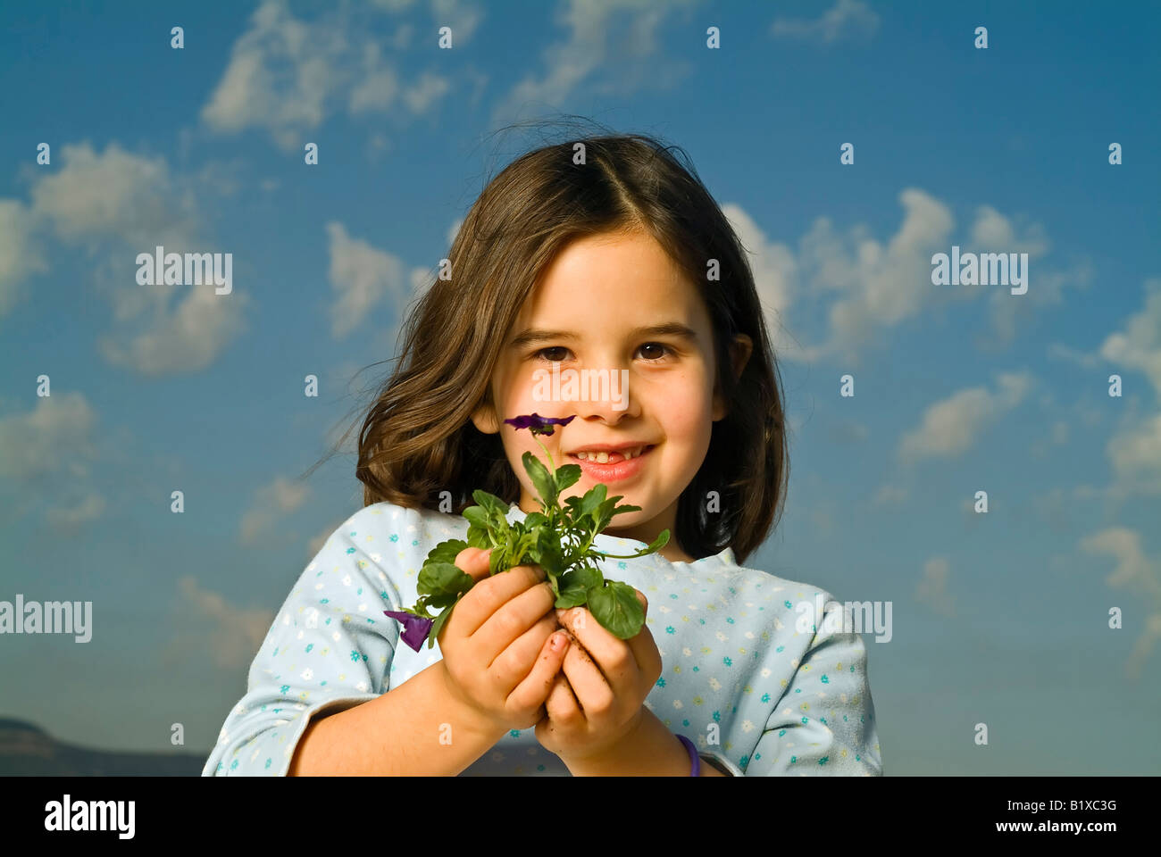 Fille avec une dent absente holding plant with flower Banque D'Images