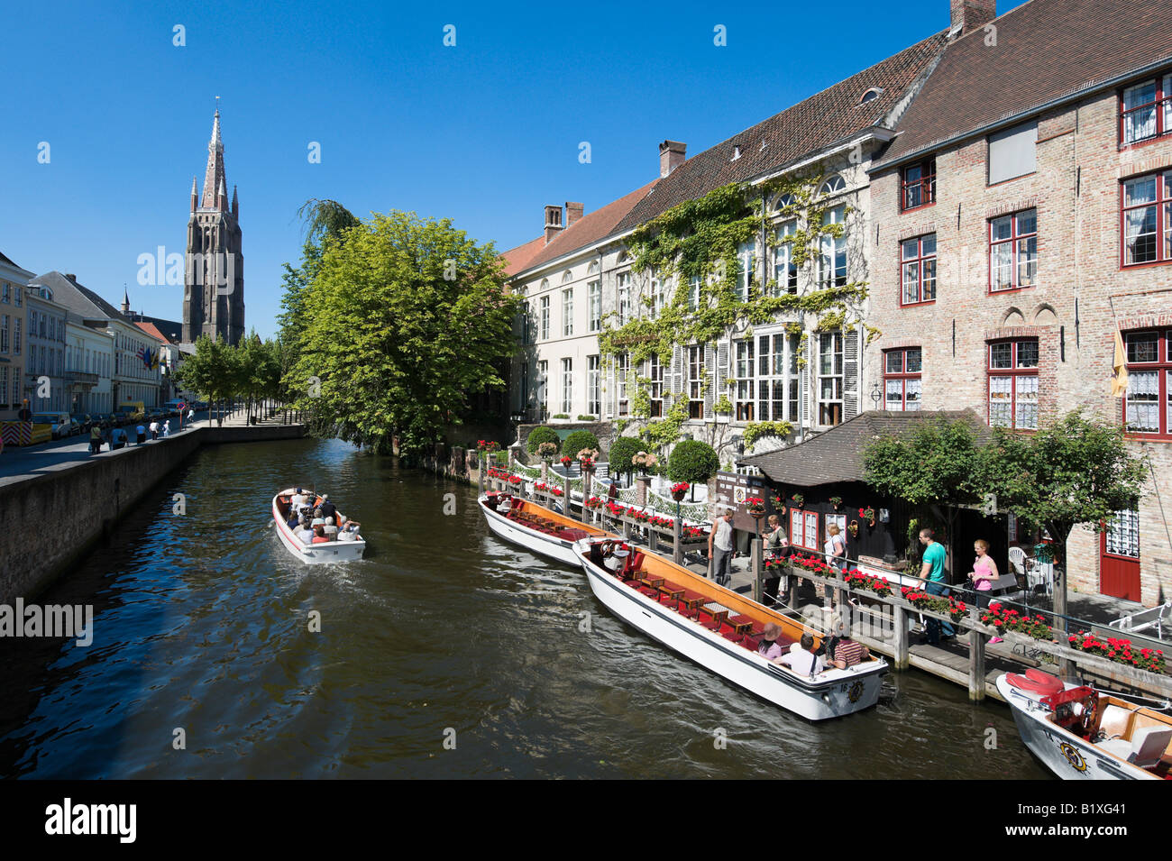 Voyage en bateau sur un canal dans le centre de la vieille ville avec Onze Lieve Vrouwekerk derrière, Bruges, Belgique Banque D'Images