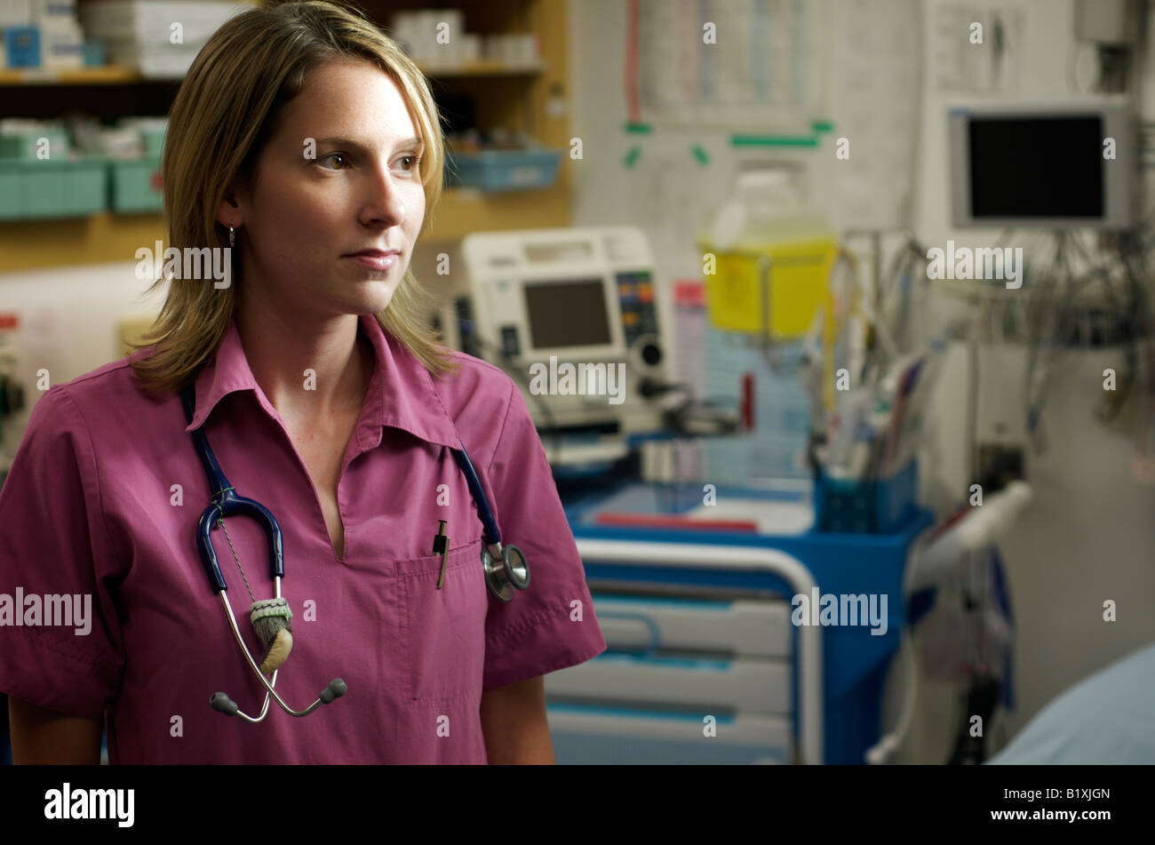 Infirmière dans scrubs dans un hôpital en souriant et posant avec un stéthoscope. Moitié du corps, posture. Banque D'Images