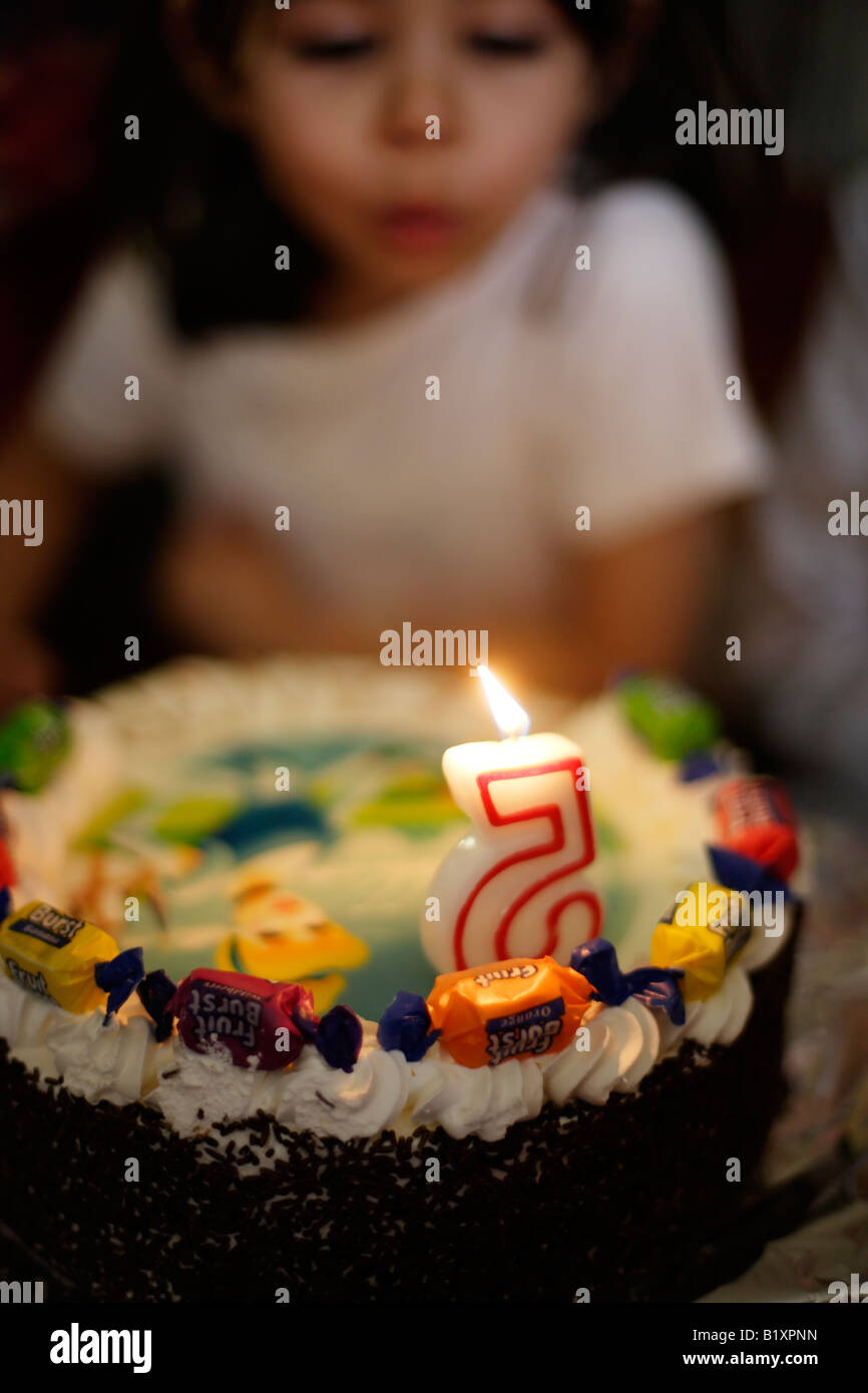 Petite fille de cinq ans souffle les bougie sur son gâteau d'anniversaire à son parti Banque D'Images