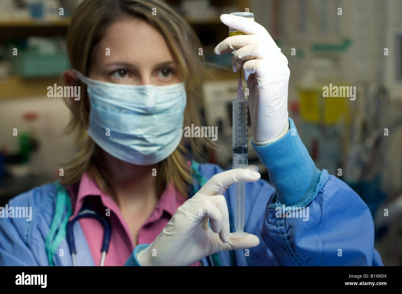 Infirmière dans scrubs avec masque de visage se prépare à une aiguille. L'hôpital l'arrière-plan. Banque D'Images