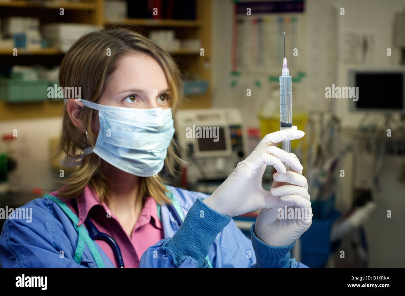 Infirmière dans scrubs avec masque de visage se prépare à une aiguille. L'hôpital l'arrière-plan. Banque D'Images