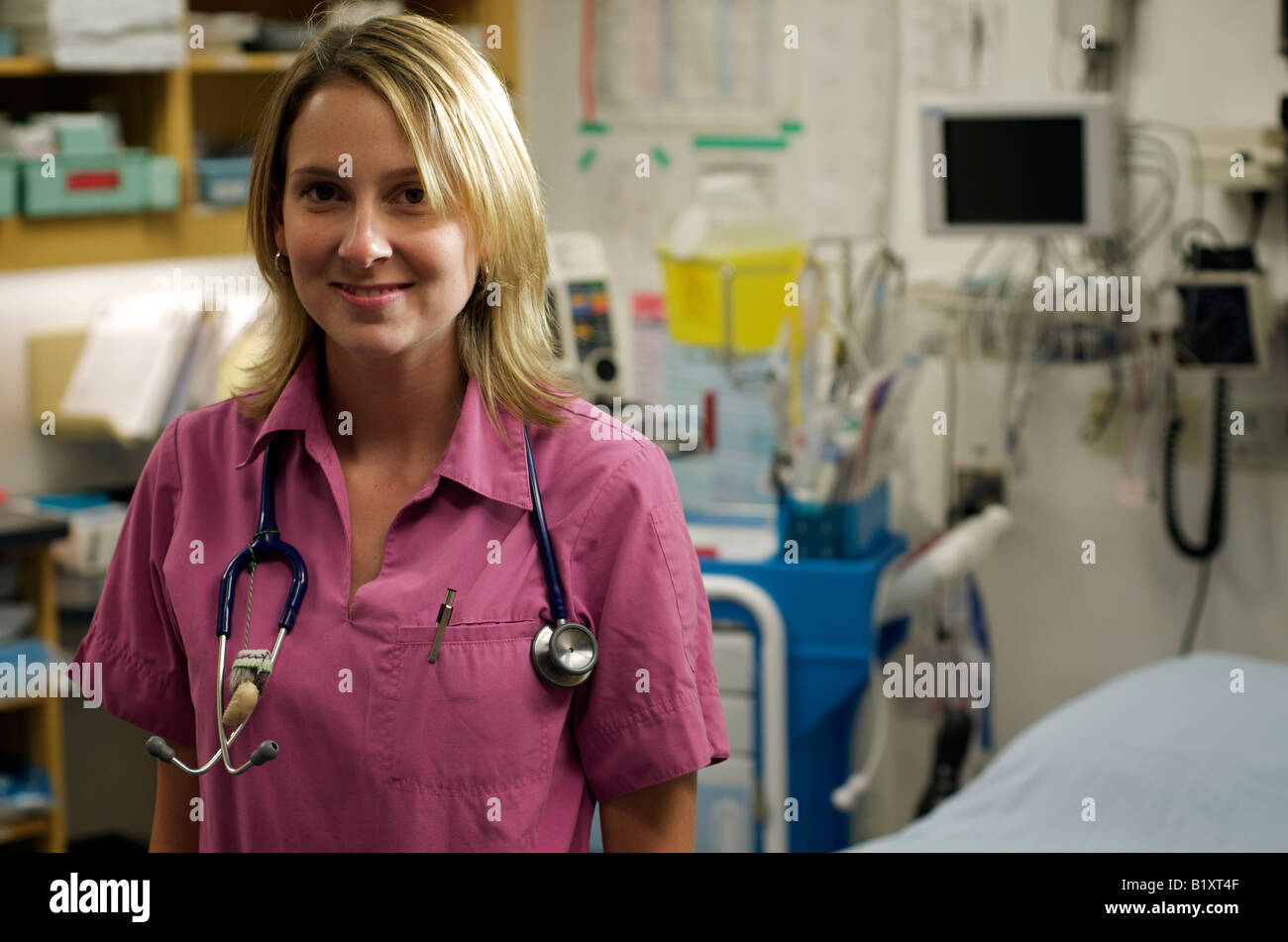 Infirmière dans scrubs dans un hôpital en souriant et posant avec un stéthoscope. Moitié du corps, posture. Banque D'Images
