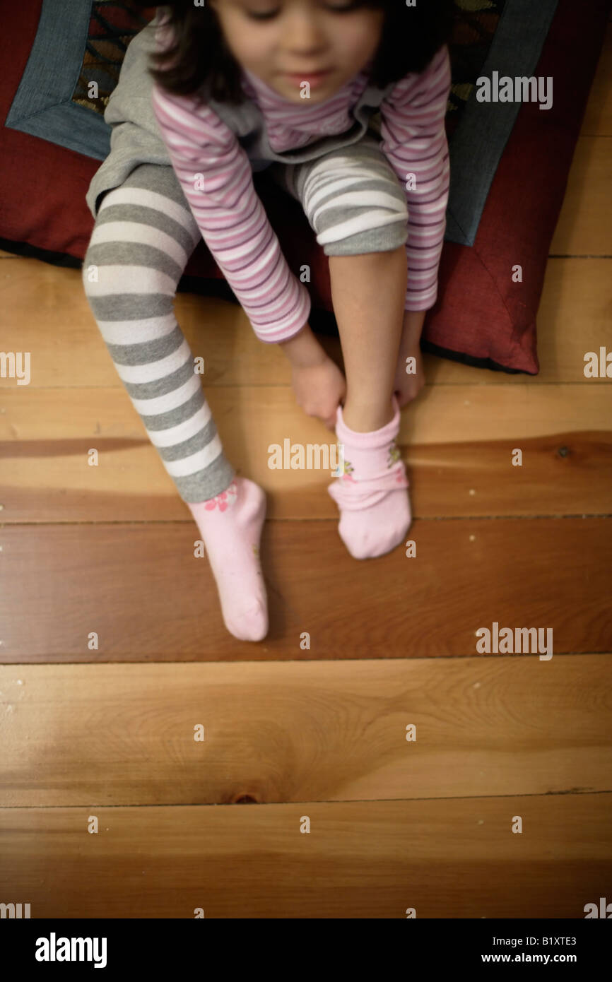 Jeune fille âgée de 4 ans tire sur ses chaussettes rose Photo Stock - Alamy