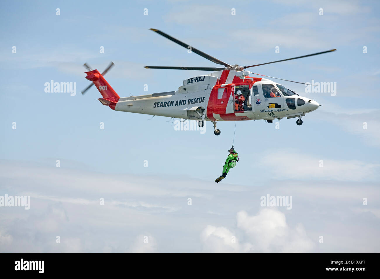 Recherche et sauvetage de l'équipage de l'hélicoptère SAR de nageurs-sauveteurs en mer s'abaisse Banque D'Images