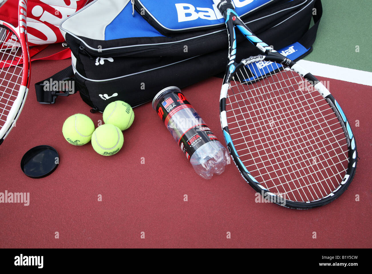 Deux sacs de raquette de tennis avec deux raquettes de tennis fixant  traversé sur le dessus et un contenant de balles de tennis sur un court de  tennis Photo Stock - Alamy