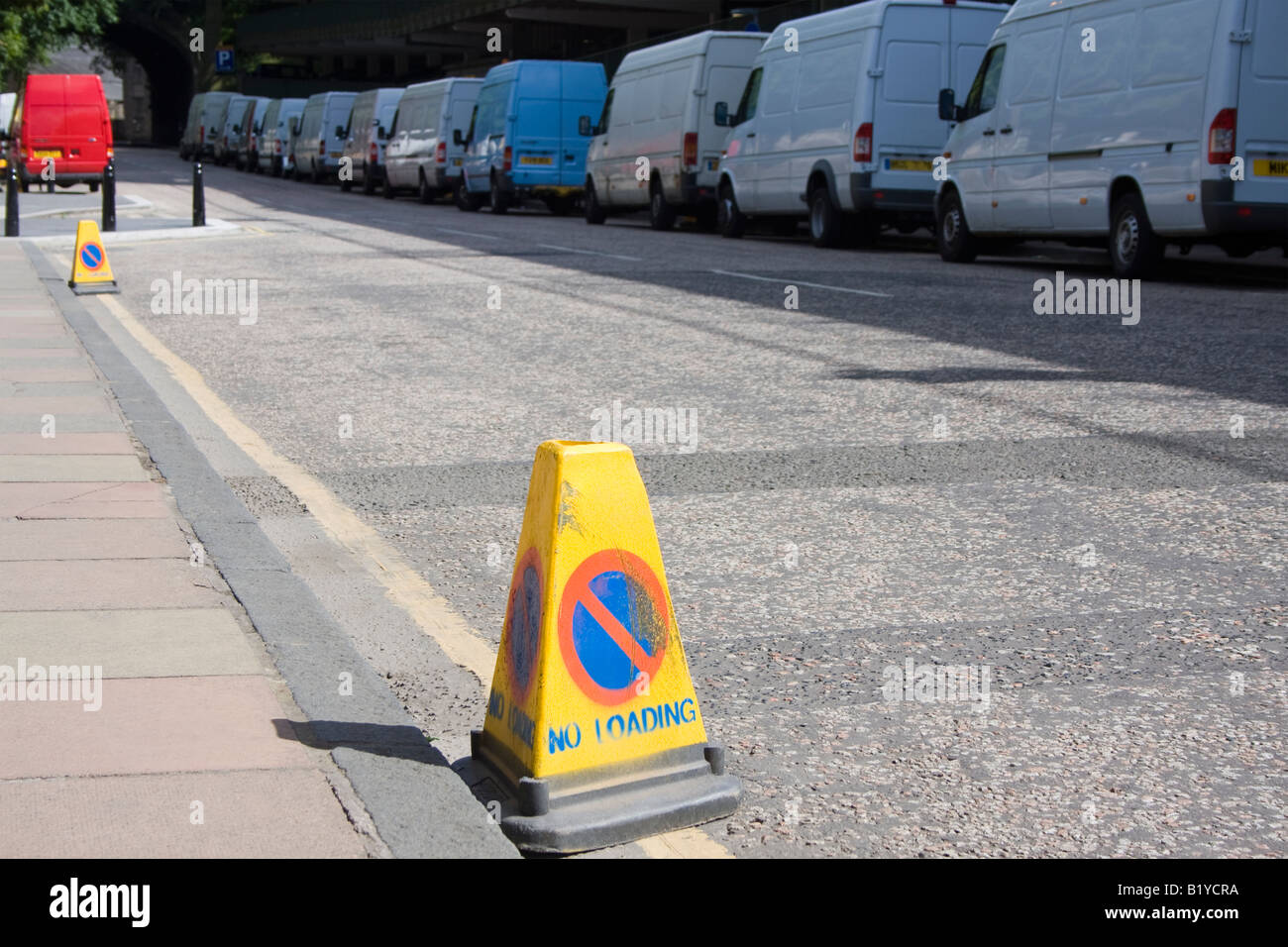 Une ligne de cars en stationnement sur une rue avec 'Pas de chargement' placé sur les cônes de la route. Banque D'Images