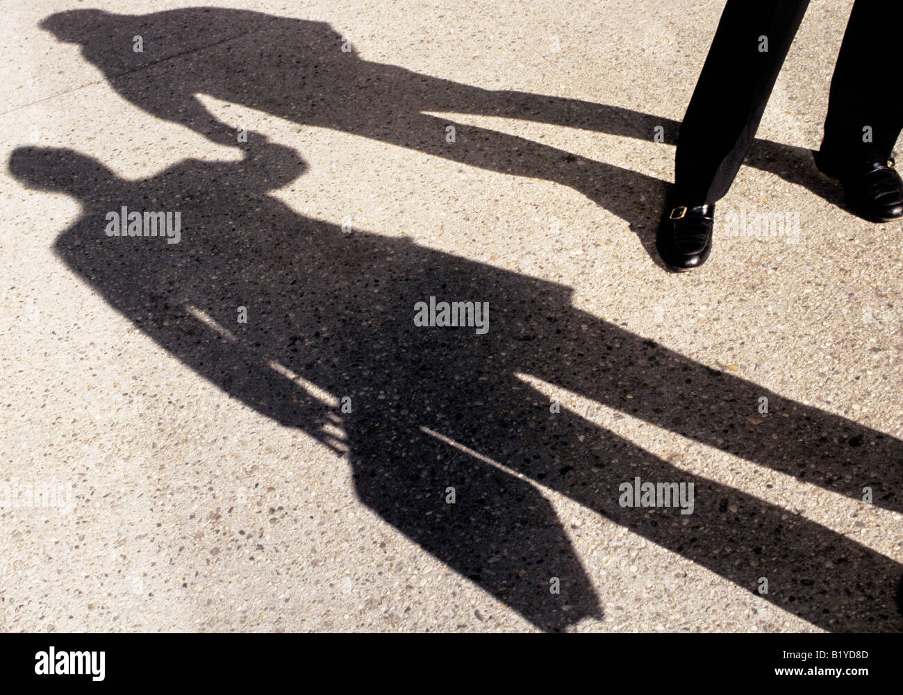 Ombres sur la chaussée ou le trottoir. Deux hommes d'affaires debout et parlant, se rencontrant dans la rue, se serrant la main en signe d'amitié. Banque D'Images