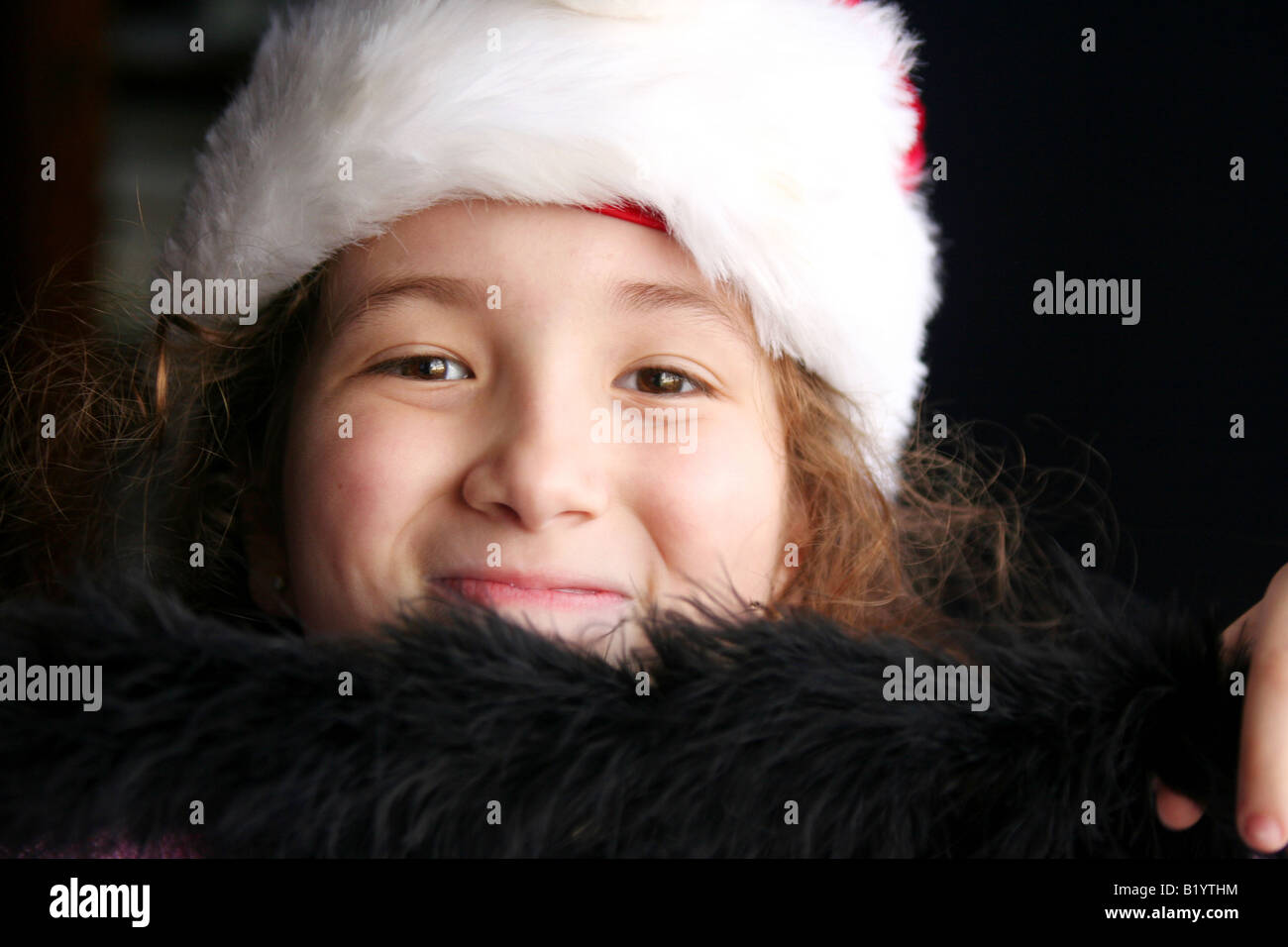 Jeune fille souriante portant un diadème noir et un chapeau de noël. Banque D'Images