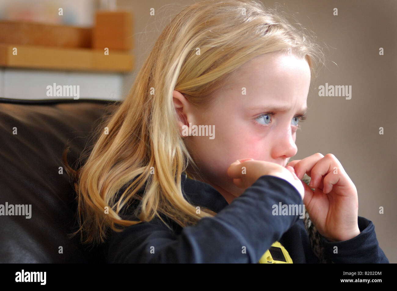 Photo de jeune fille regarder la télévision ou un DVD tout en mordant sa nailsl dans maison familiale UK Banque D'Images