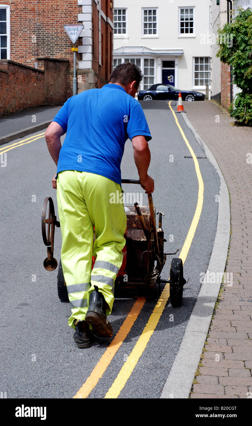 L'homme double peinture lignes jaunes sur la route, UK Banque D'Images