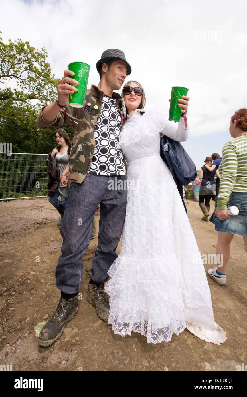 Un couple heureux avec bières, la femme est dans une robe de mariage, Glastonbury Festival 2008 Banque D'Images