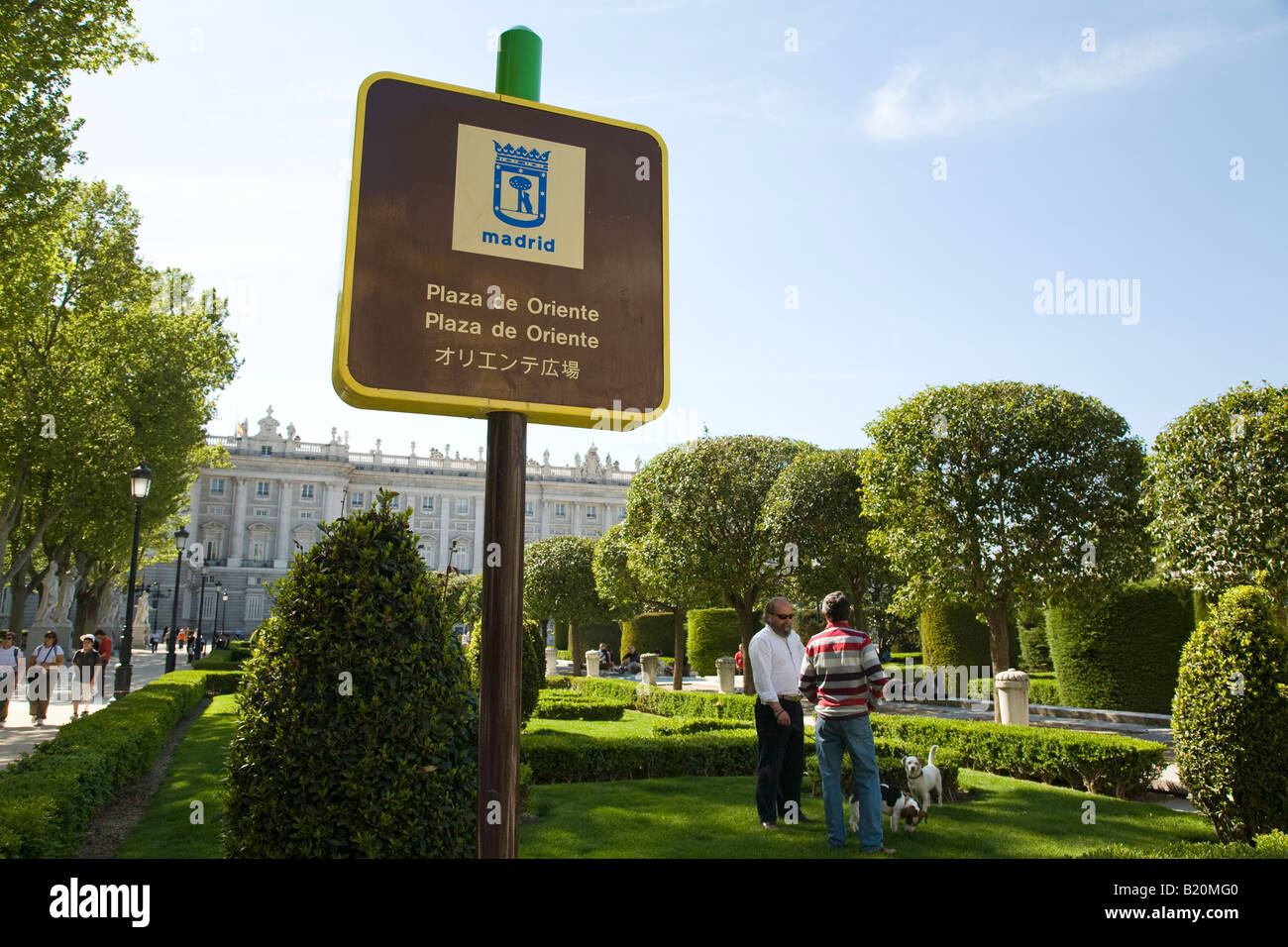 Espagne Madrid deux hommes avec des chiens en laisse dans les jardins de la Plaza de Oriente près de Royal Palace sign in Espagnol Anglais Banque D'Images