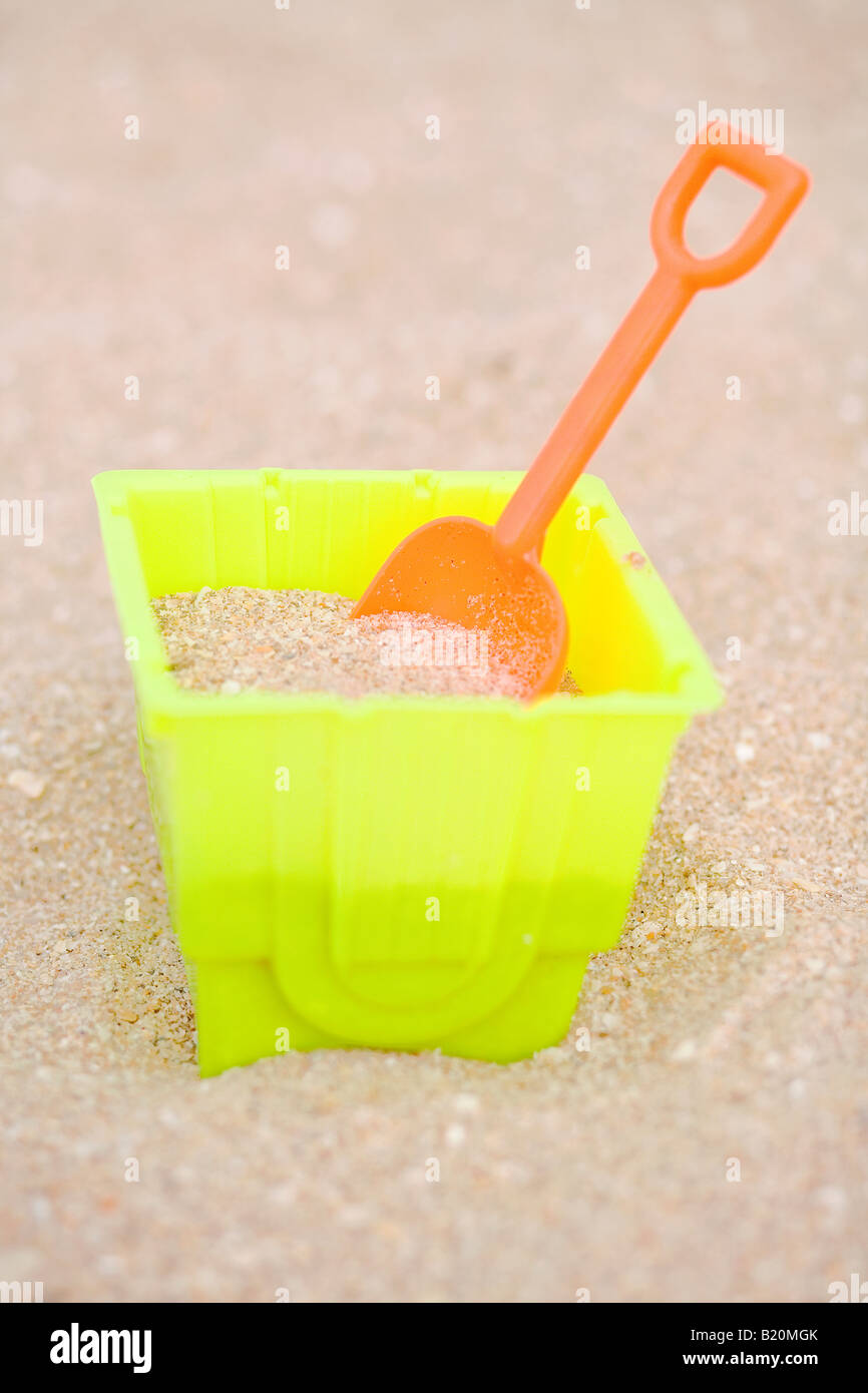 Des jouets de plage en plastique coloré dans le sable. Banque D'Images