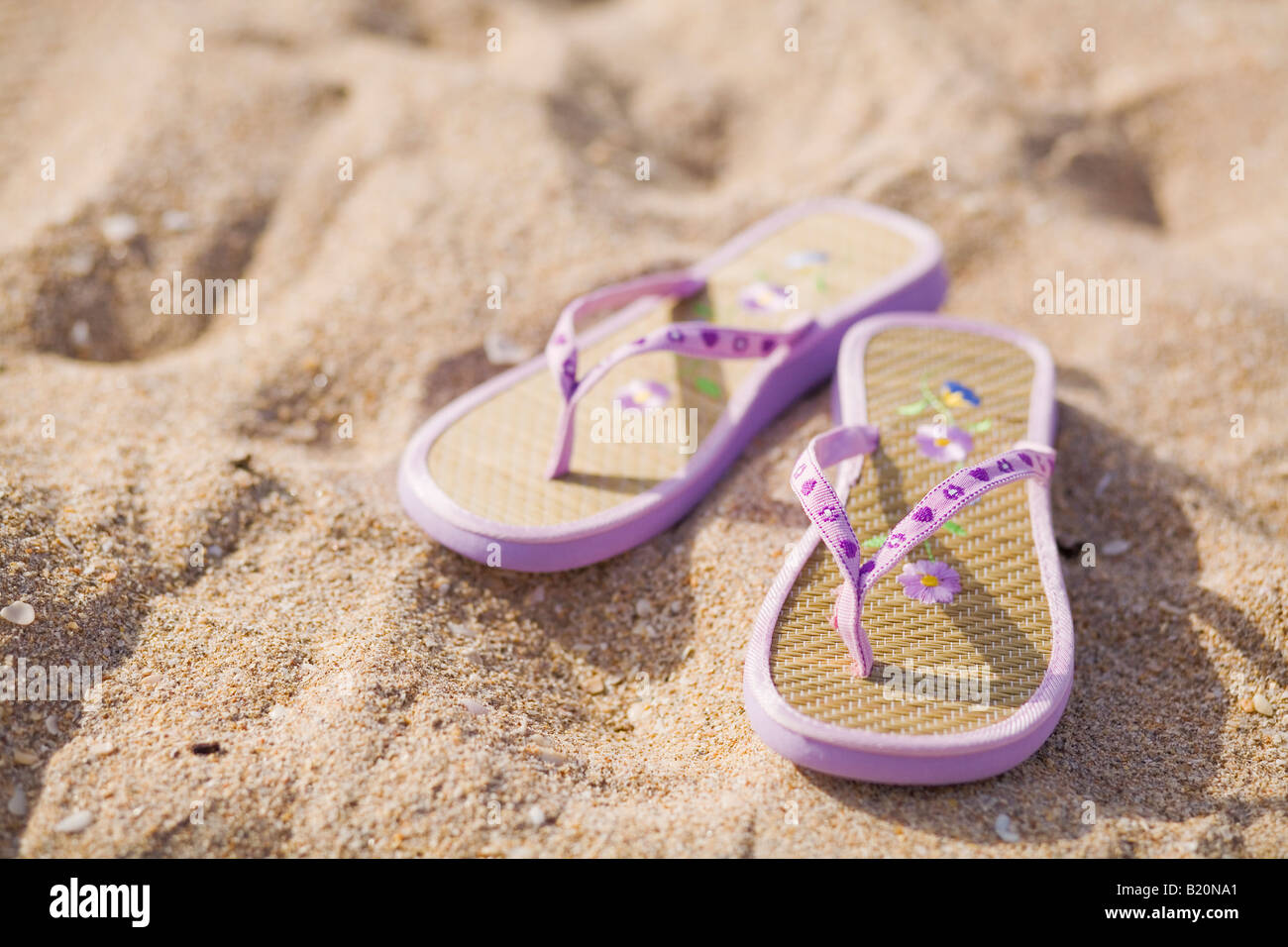 Paire de tongs violet sur la plage. Banque D'Images