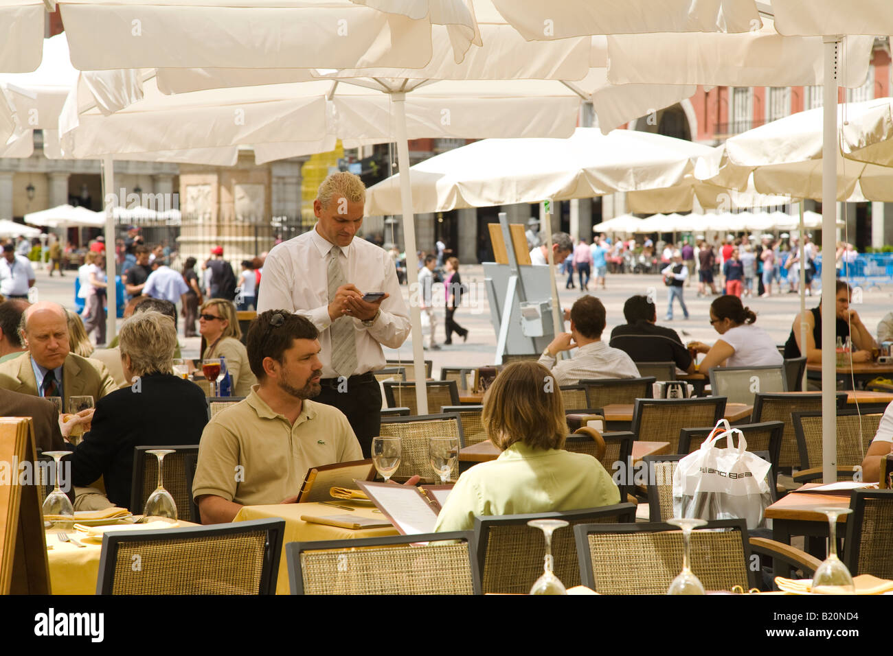 Espagne Madrid waiter taking order sur le pad au parapluie en plein air sur la Plaza Mayor table commande de menu alimentaire couple Banque D'Images