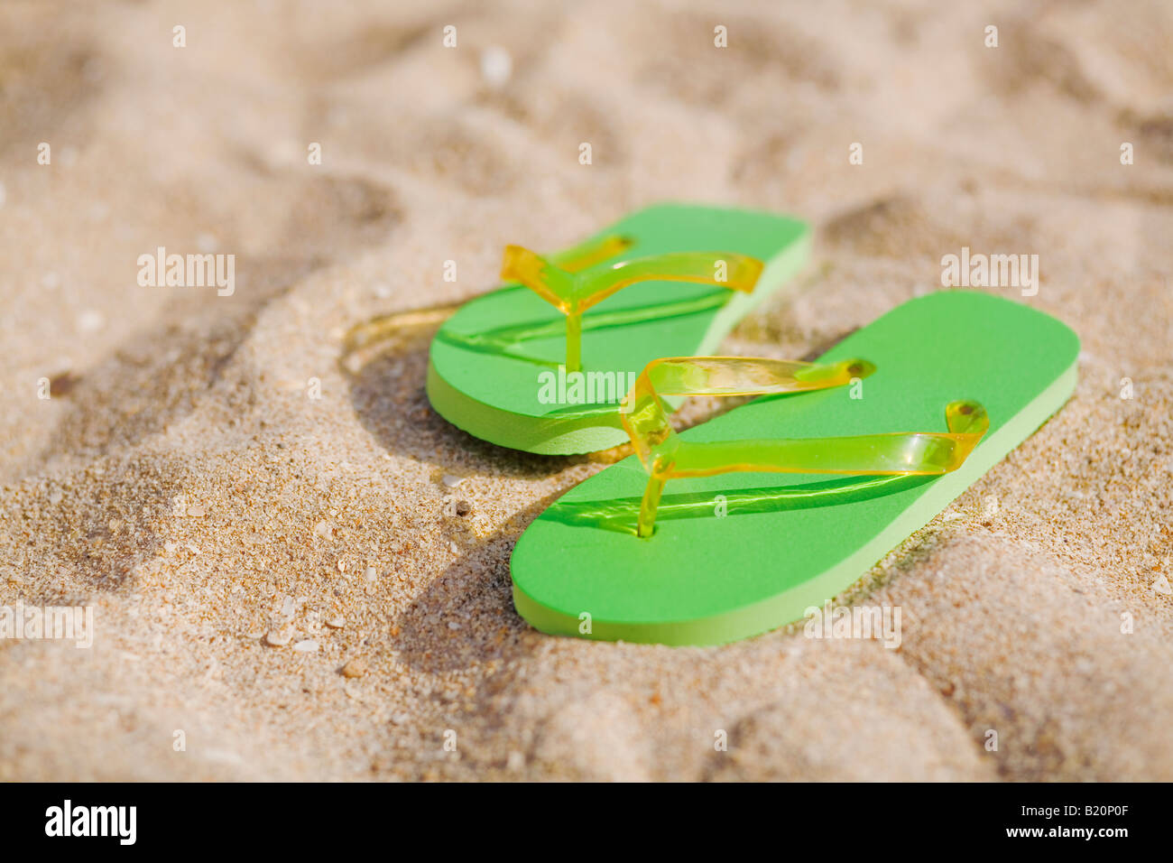 Paire de tongs vert sur la plage. Banque D'Images