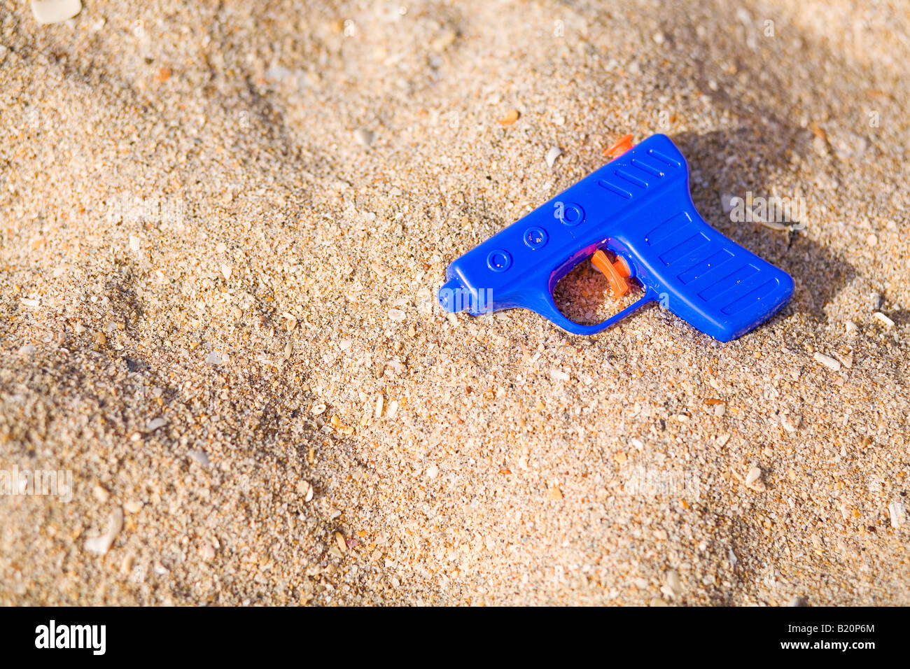 Pistolet à eau bleu dans le sable sur la plage. Banque D'Images