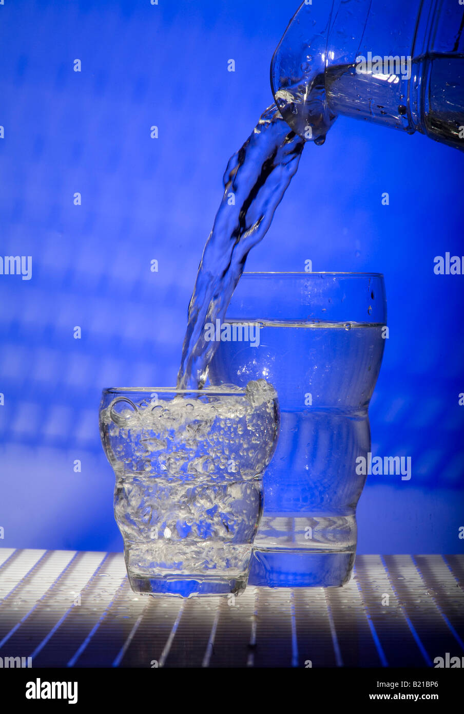 Verse de l'eau cruche dans plus petit de deux verres. Banque D'Images