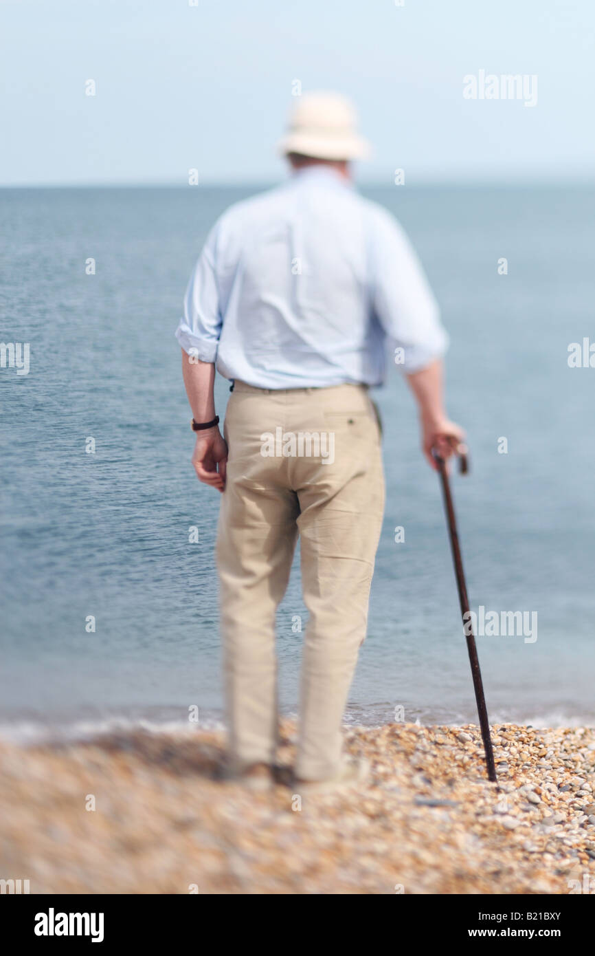 Homme plus âgé avec bâton de marche se tenait sur la plage Banque D'Images