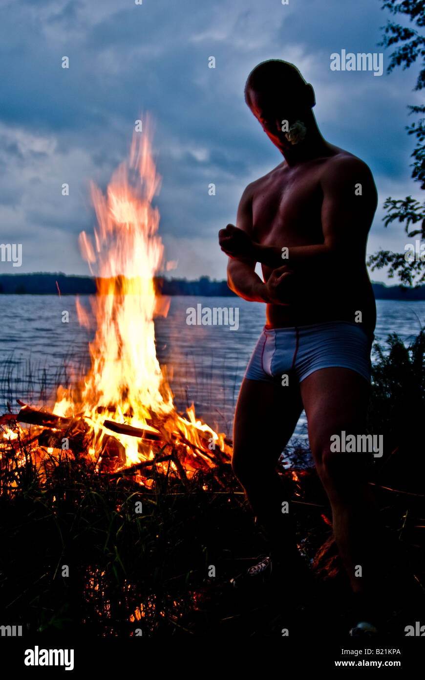 Une folle finn fléchit ses muscles à côté d'un milieu traditionnel finlandais pyre Banque D'Images