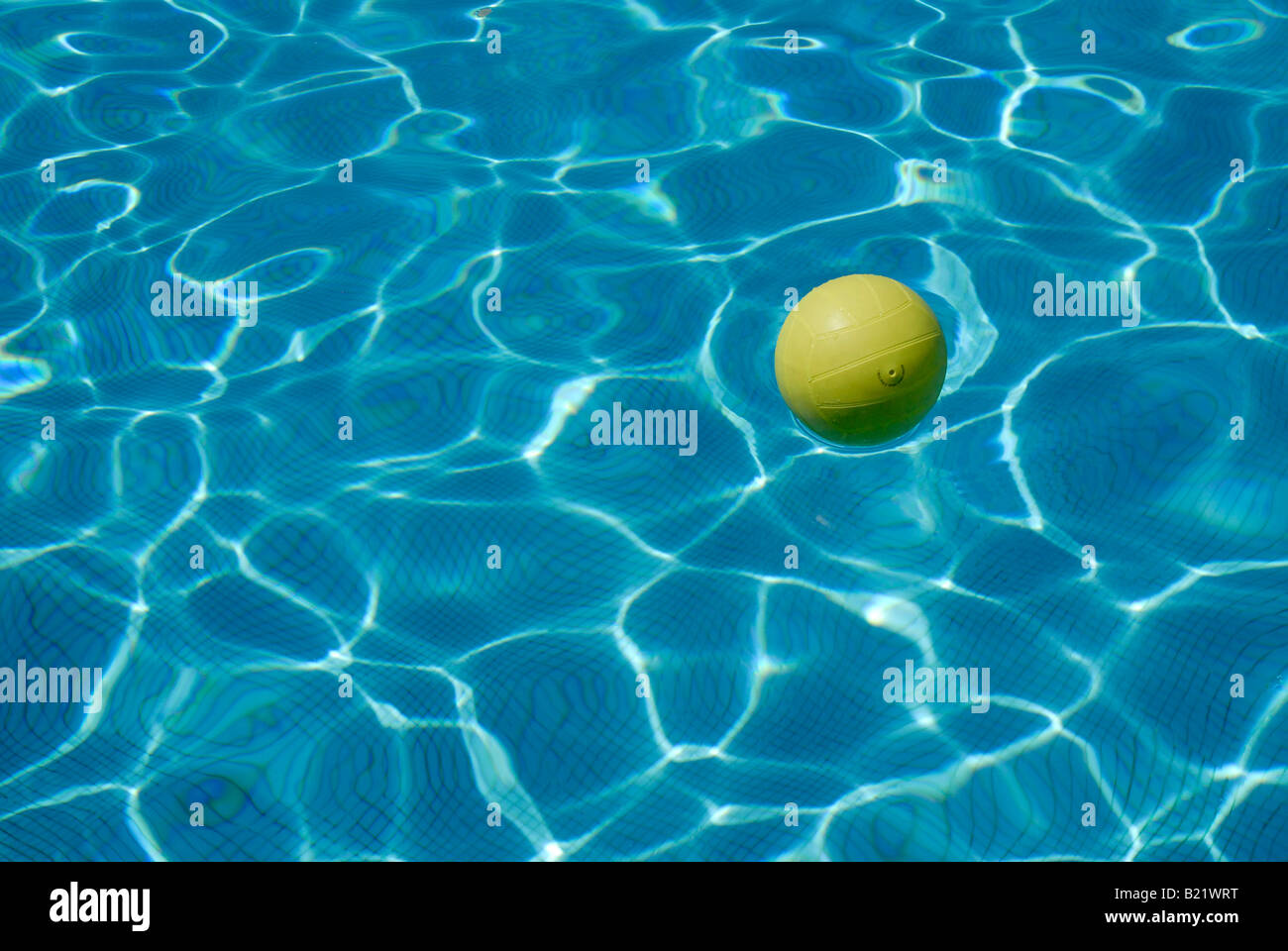 Water-polo jaune balle sur la surface d'une piscine bleu Banque D'Images