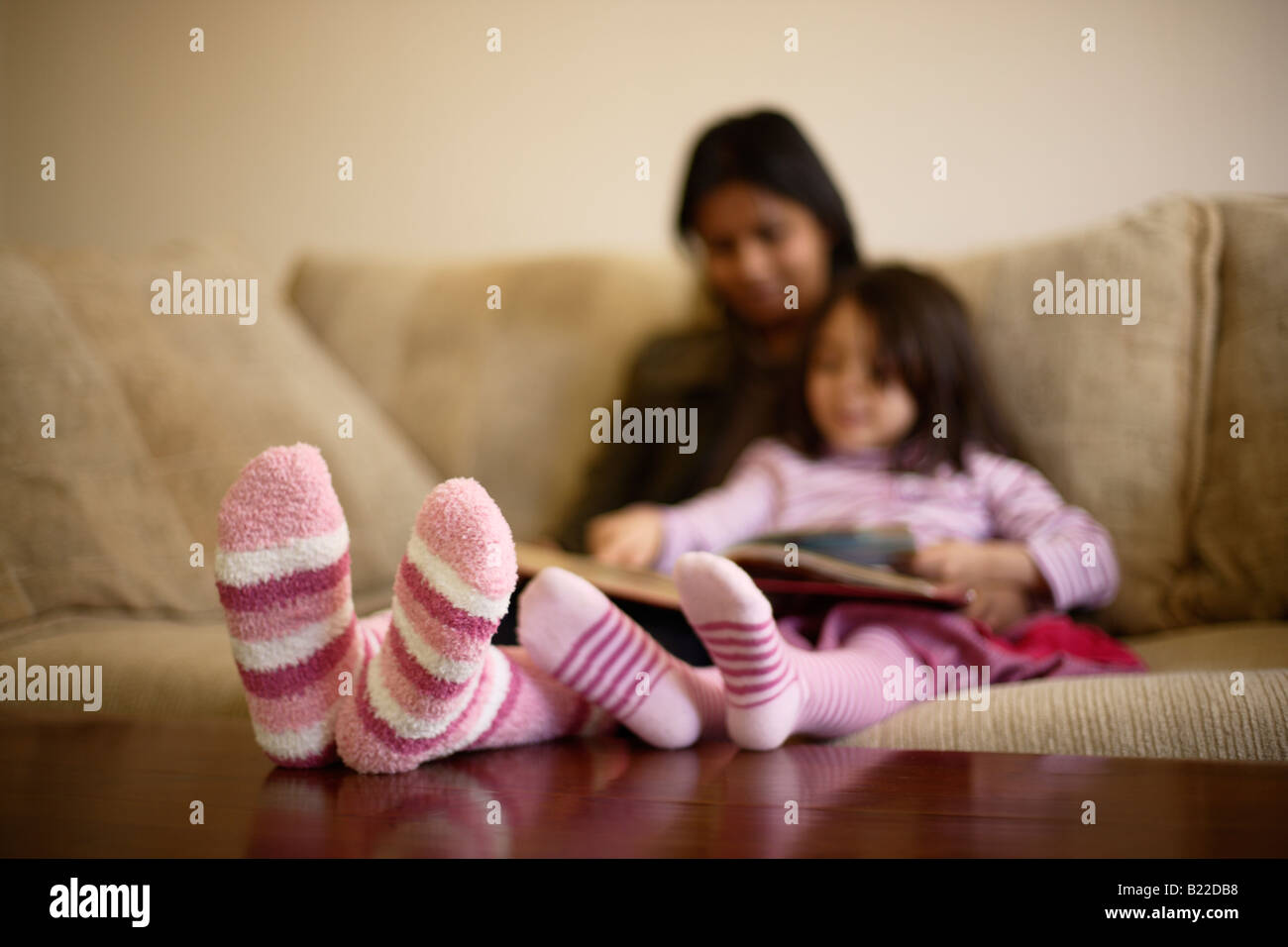 Mère indienne 30s et mixed race 4 fille lire un livre portant des  chaussettes rayées rose Photo Stock - Alamy