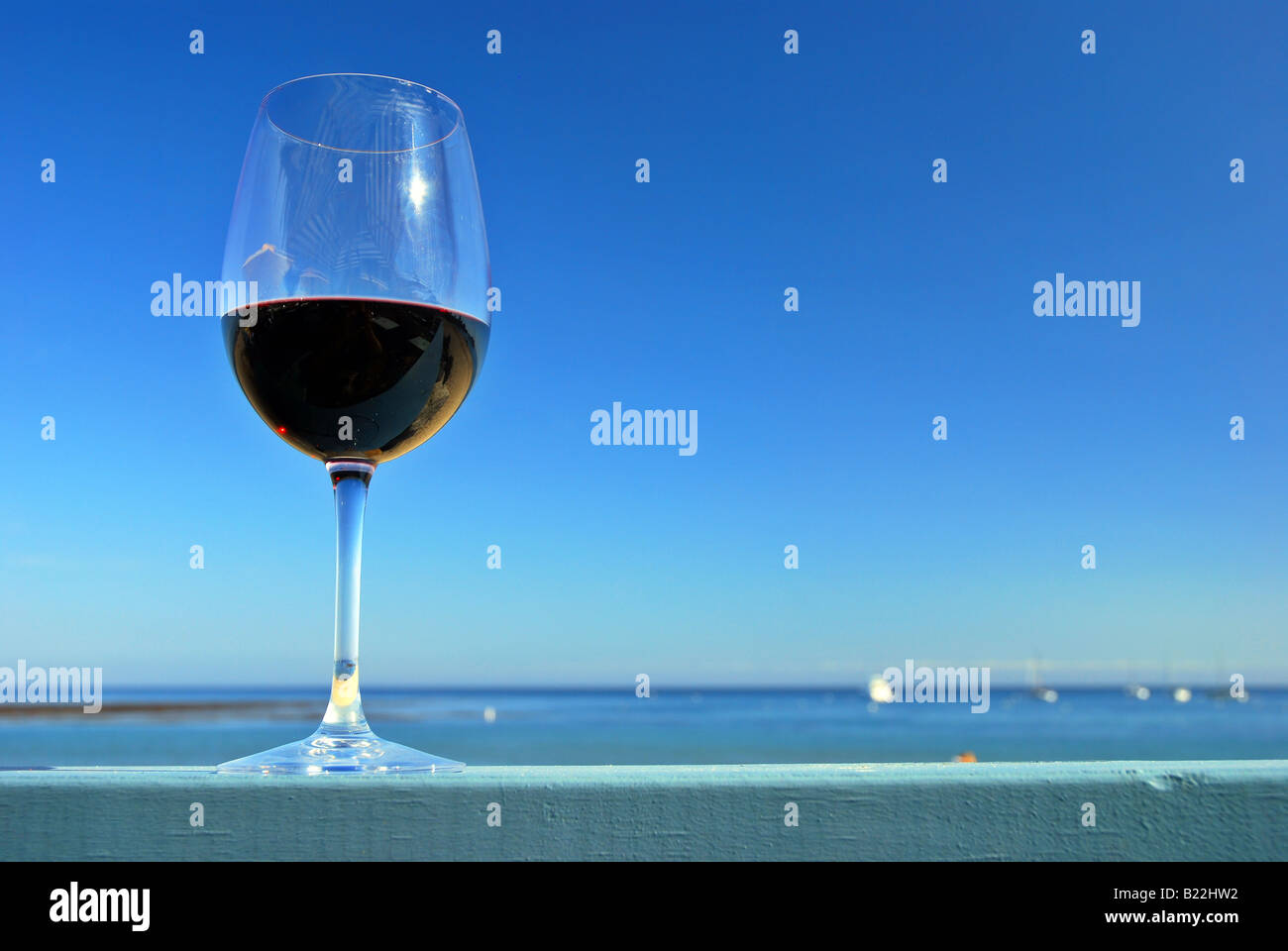 Verre de vin rouge sur un restaurant deck garde-fous à l'océan plage Banque D'Images