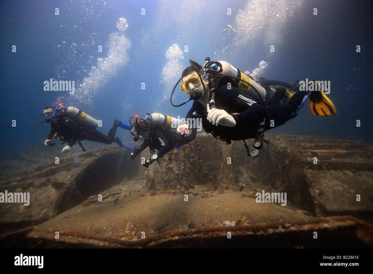 Trois plongeurs d'explorer l'épave du SS Thistlegorm dans l'égyptien de la Mer Rouge. Banque D'Images