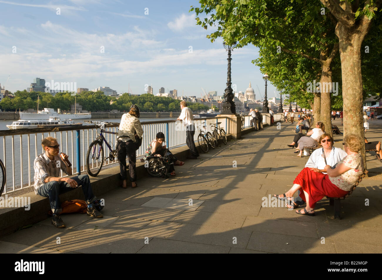 Les gens se font chauffer la couenne au soleil le long de la Tamise avec la Cathédrale St Paul s dans la distance London UK Banque D'Images