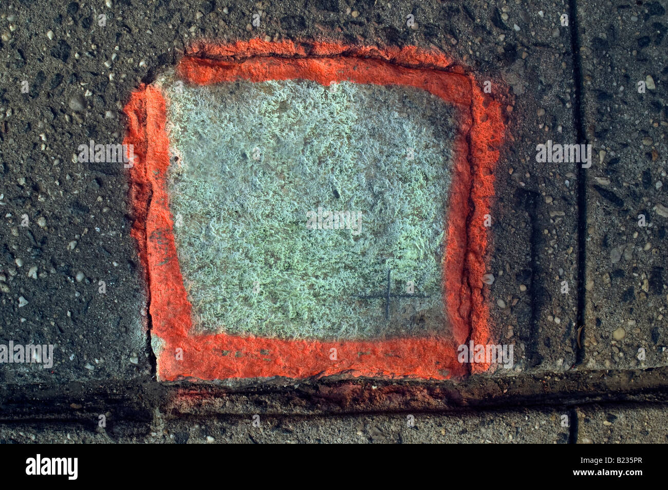 Close up de forme carré de couleur orange-géomètre s mark sur trottoir de béton de conglomérat Banque D'Images