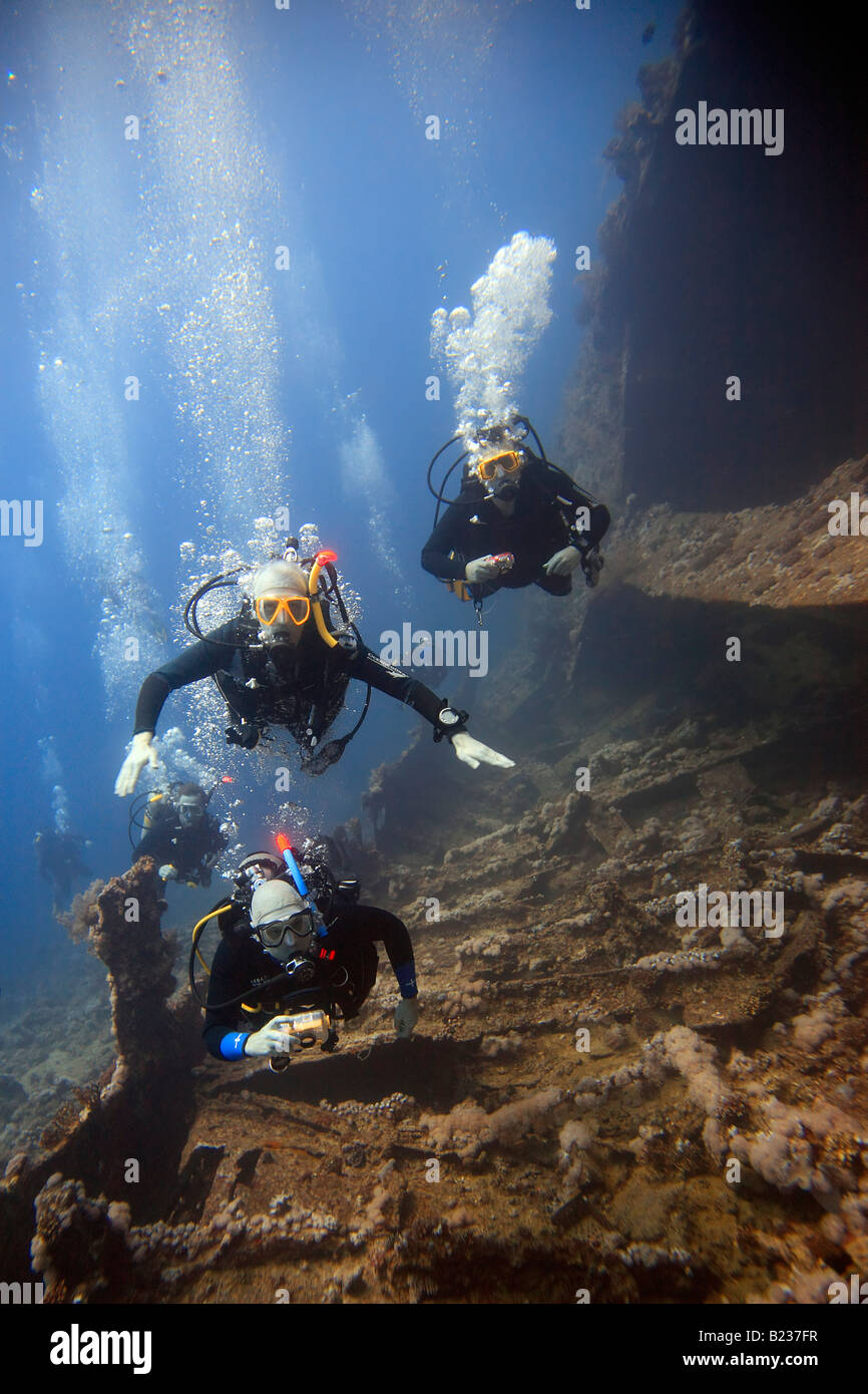 Trois plongeurs d'explorer l'épave du Dunraven égyptien dans la mer Rouge. Banque D'Images