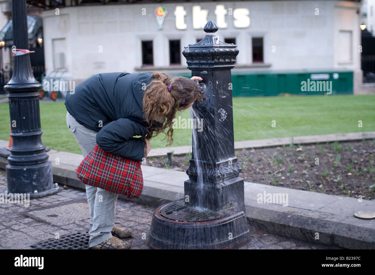 Une femme boit d'une fontaine d'eau à Londres Banque D'Images