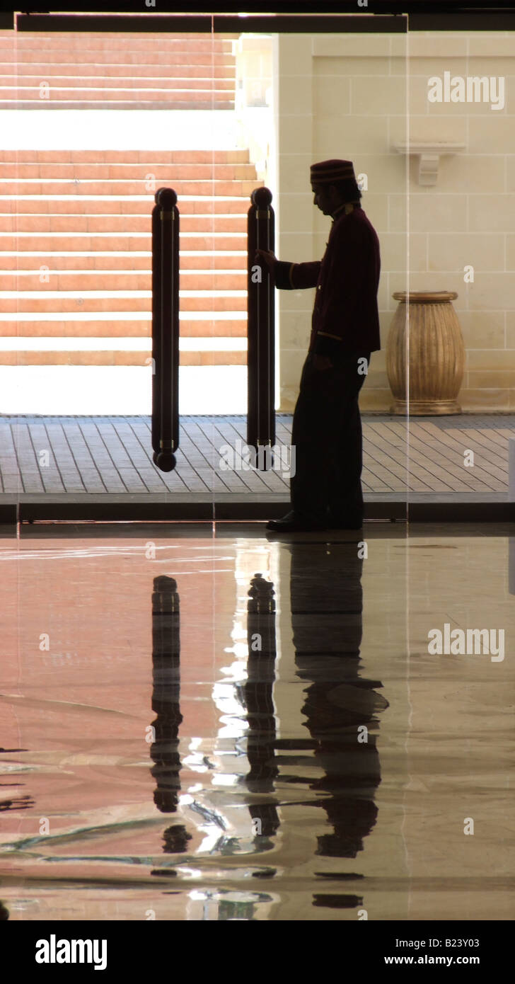 Portier de l'hôtel et portes en verre consignées dans un sol en marbre. Banque D'Images