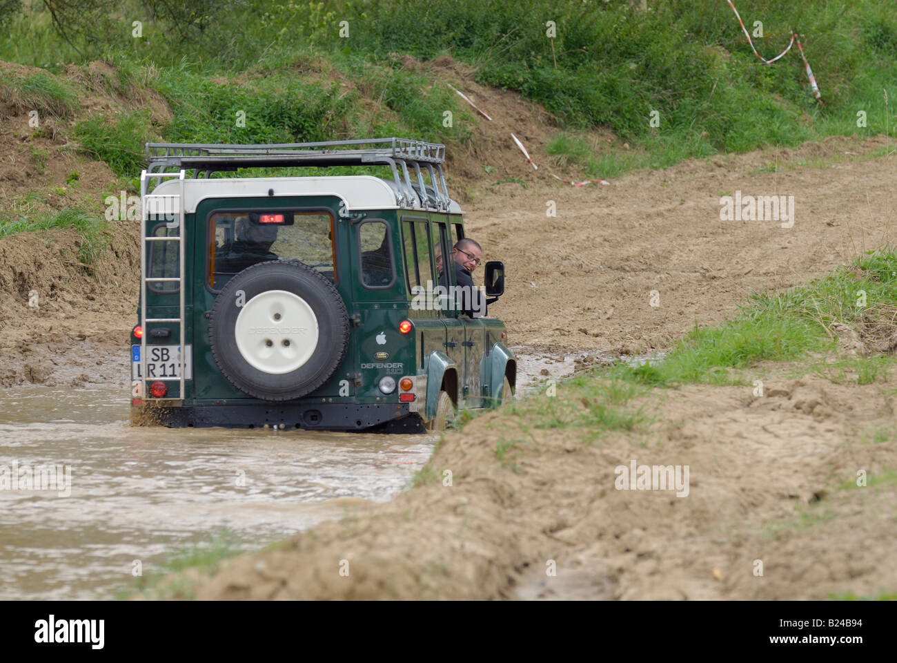 Land Rover la conduite hors route à travers un chemin de terre inondée à Bining, France. Banque D'Images