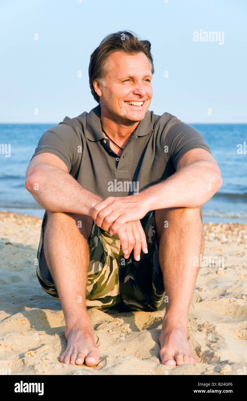 Un sourire heureux homme de 44 ans est de vous détendre sur une belle plage de sable pendant ses vacances. Banque D'Images